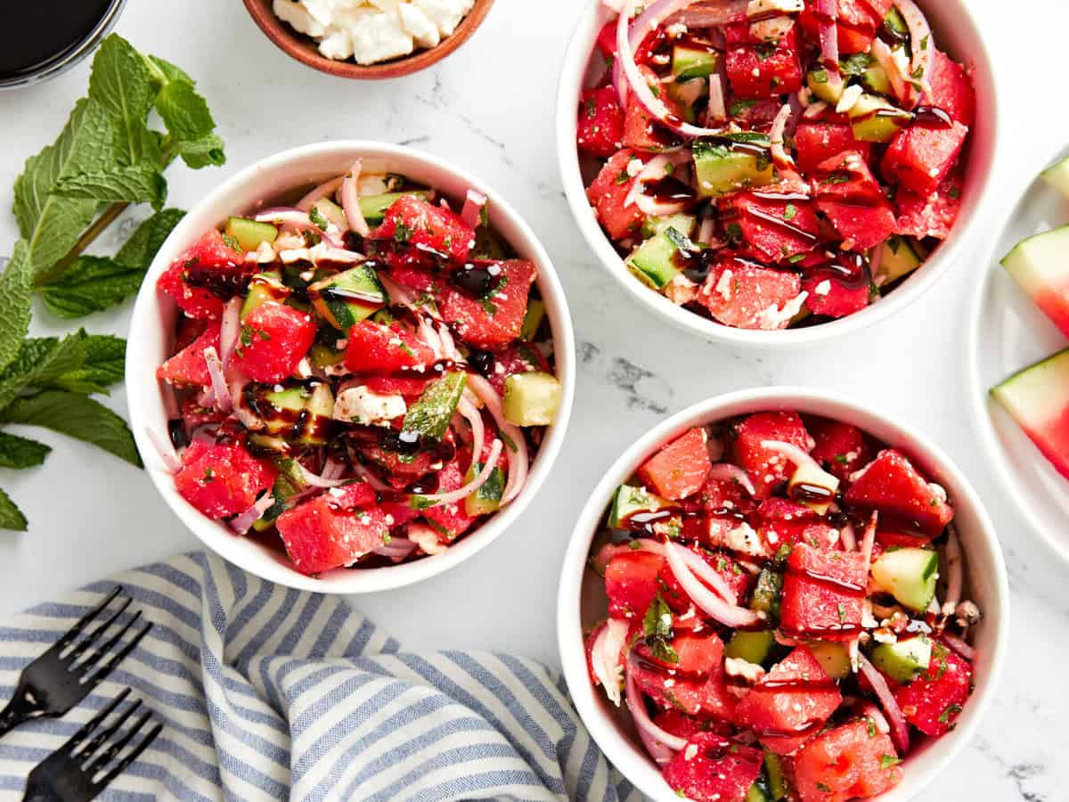 overhead view of 3 servings of watermelon and feta salad drizzled with balsamic glaze.