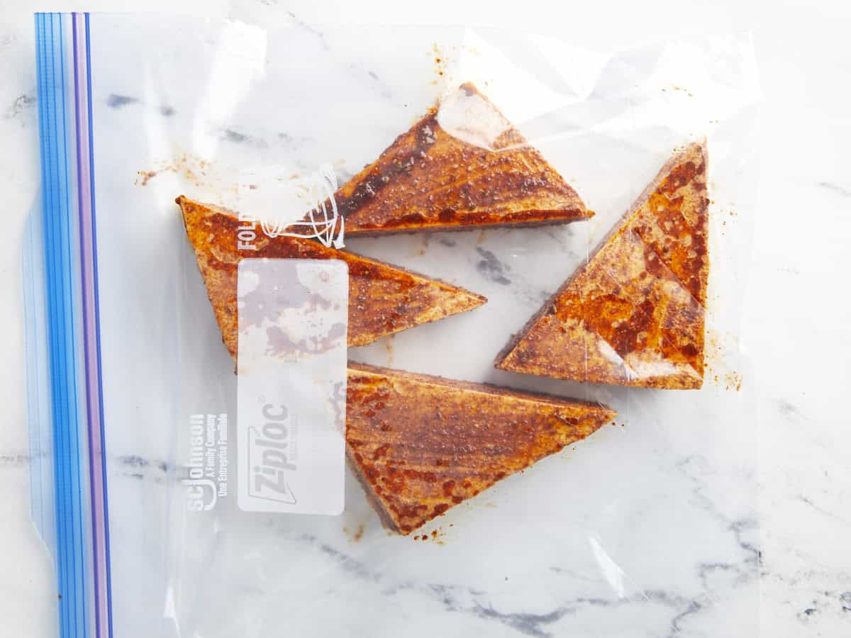 Marinaded BBQ tofu triangles in a Ziploc bag for freezing.