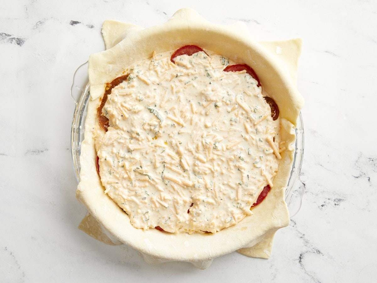 Puff pastry sheet in a glass pie pan filled with tomato pie filling