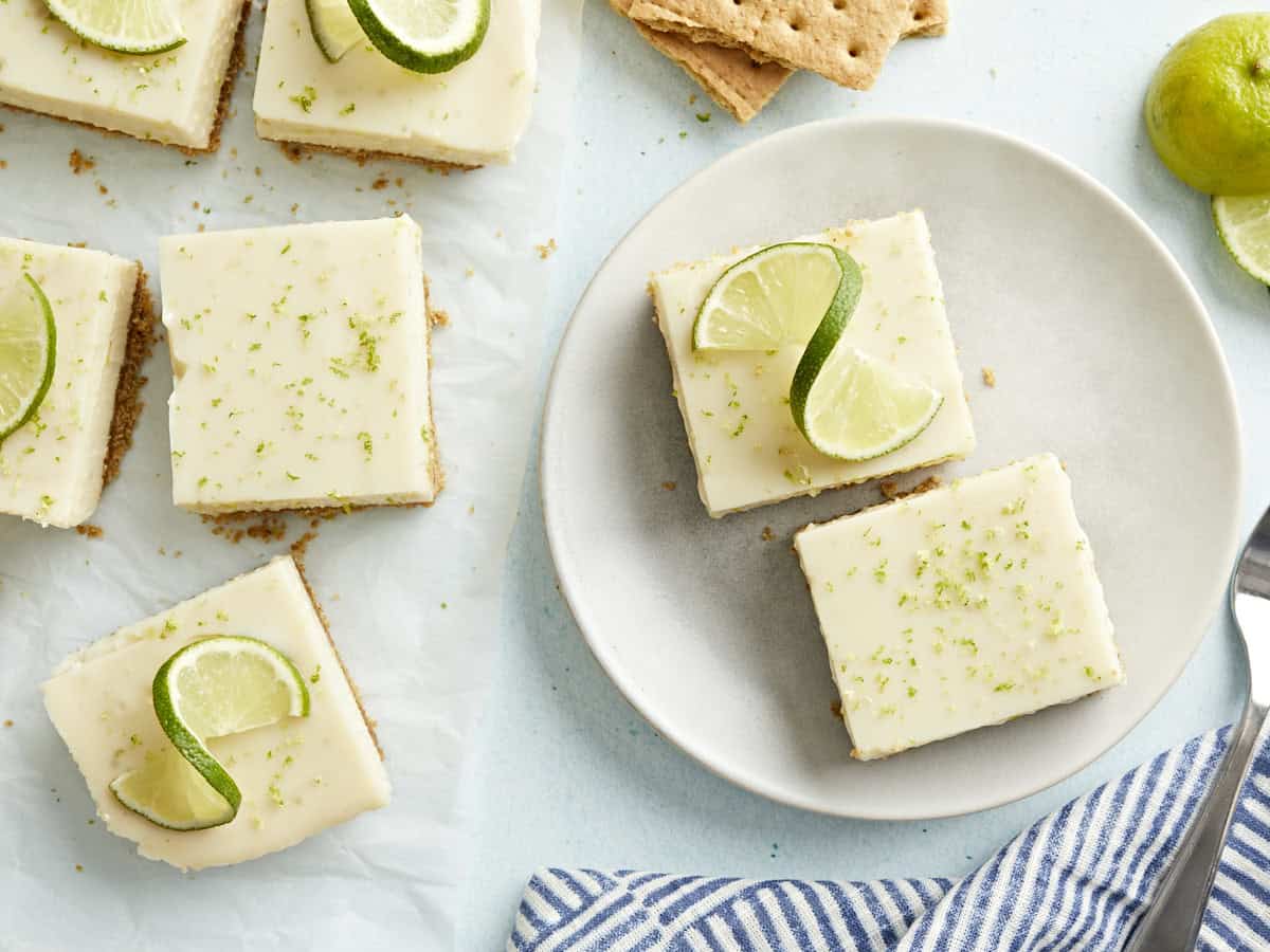 Key lime pie bars topped with lime slices on a plate.