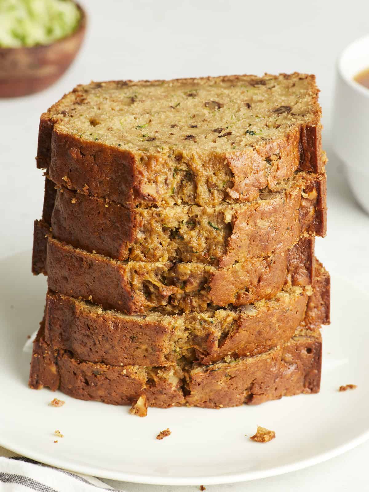 Slices of zucchini bread stacked on a white plate.