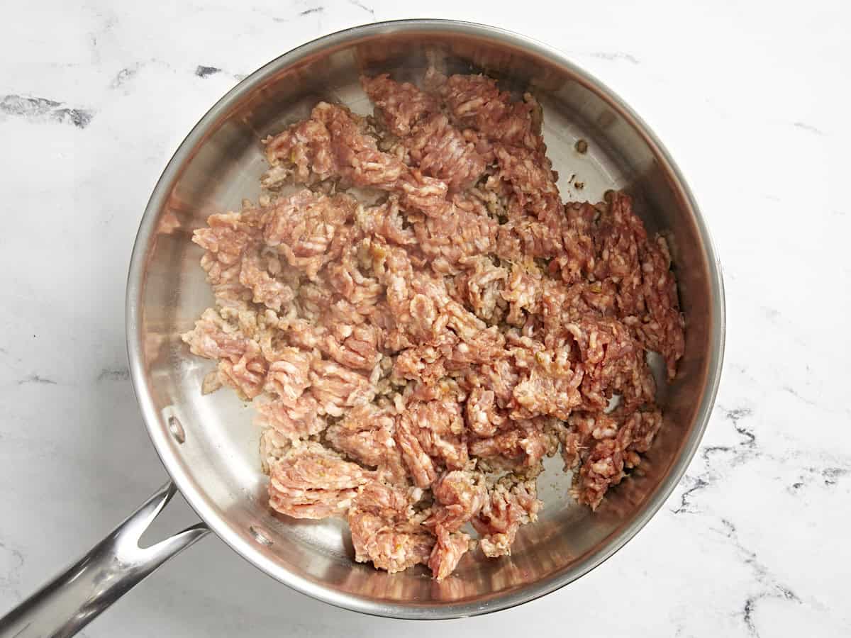 Italian sausage being cooked in a skillet.