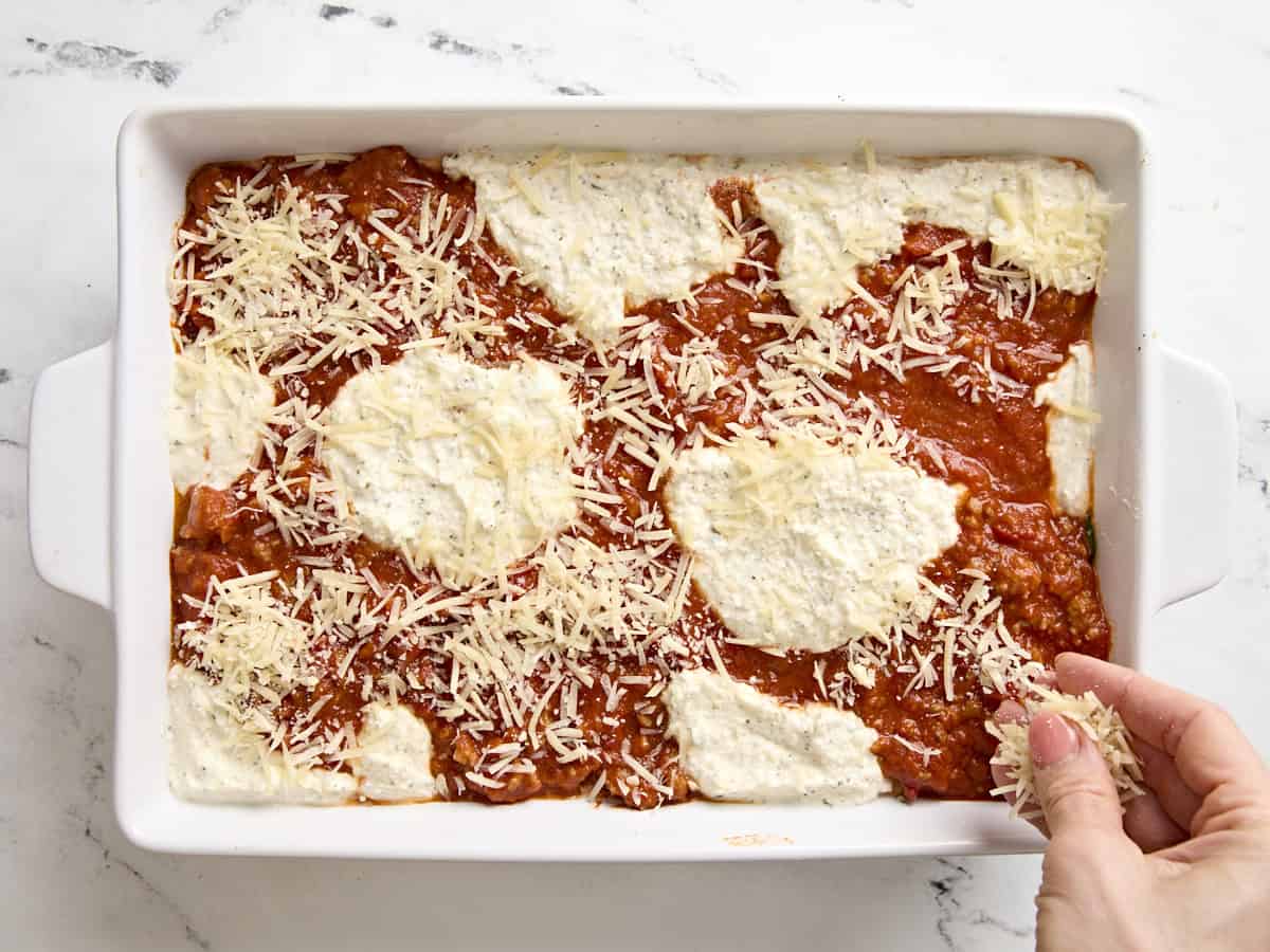 Sprinkling shredded cheese on top of zucchini lasagna