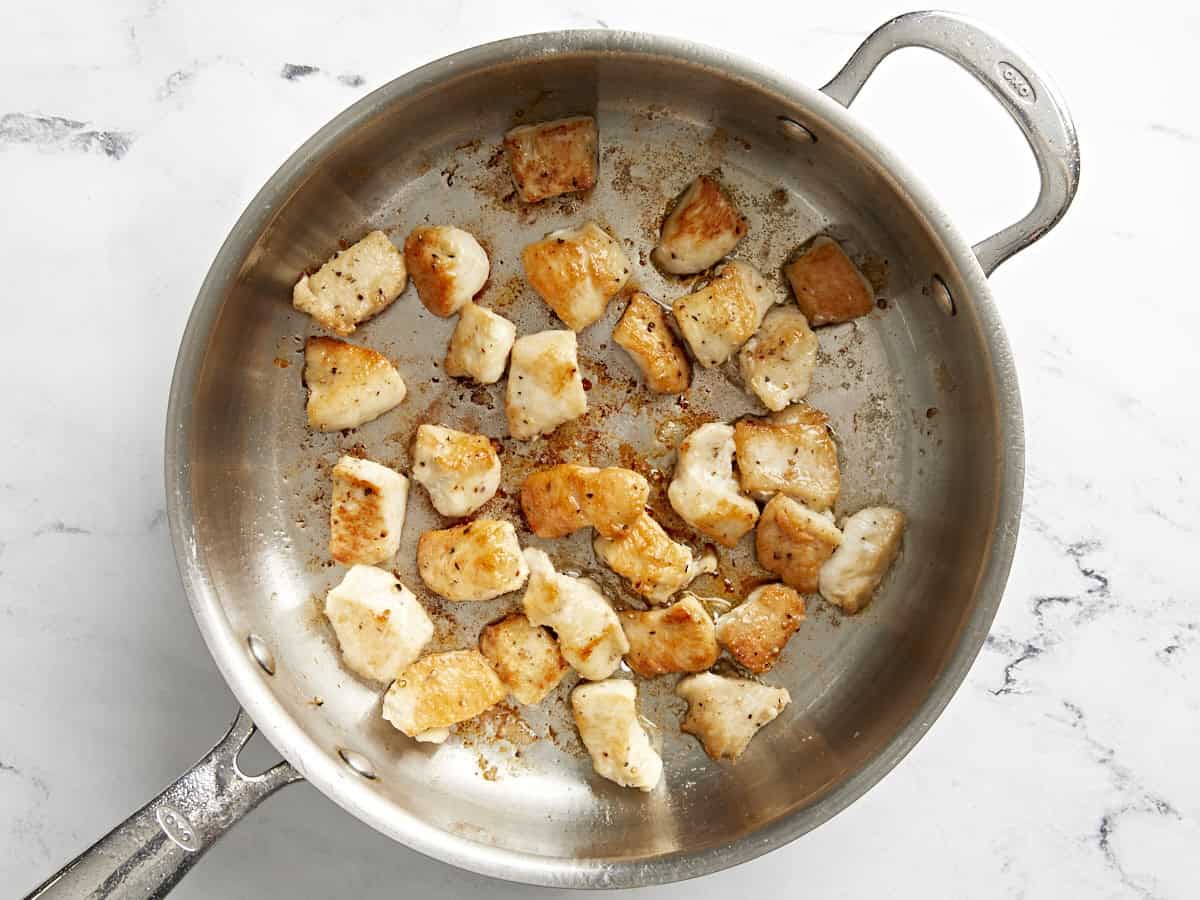 Cooked chicken pieces in a skillet.