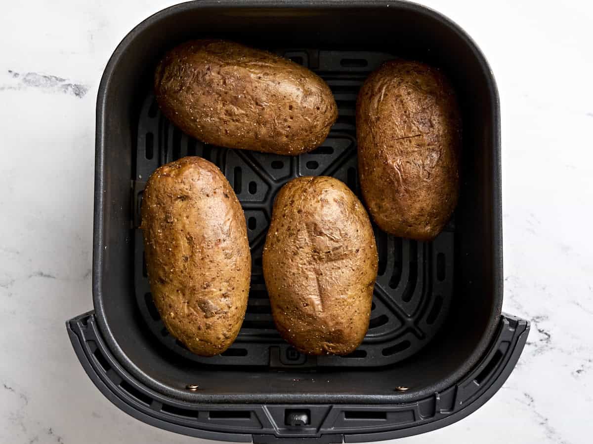 Cooked russet potatoes in an air fryer basket.