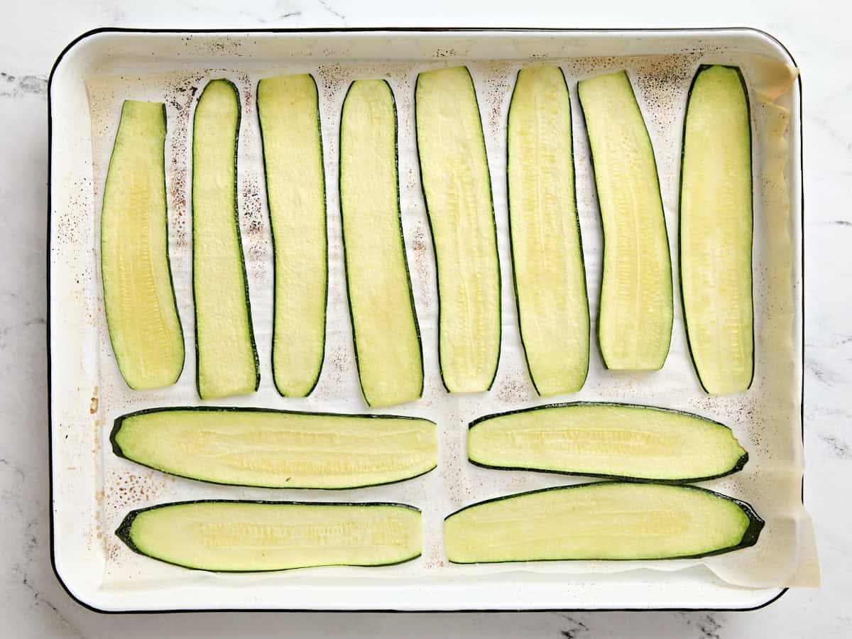 Slices of zucchini in a parchment lined baking dish