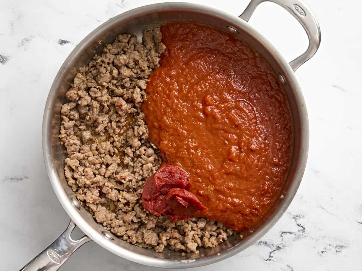 Tomato sauce, tomato paste, and ground sausage in a skillet