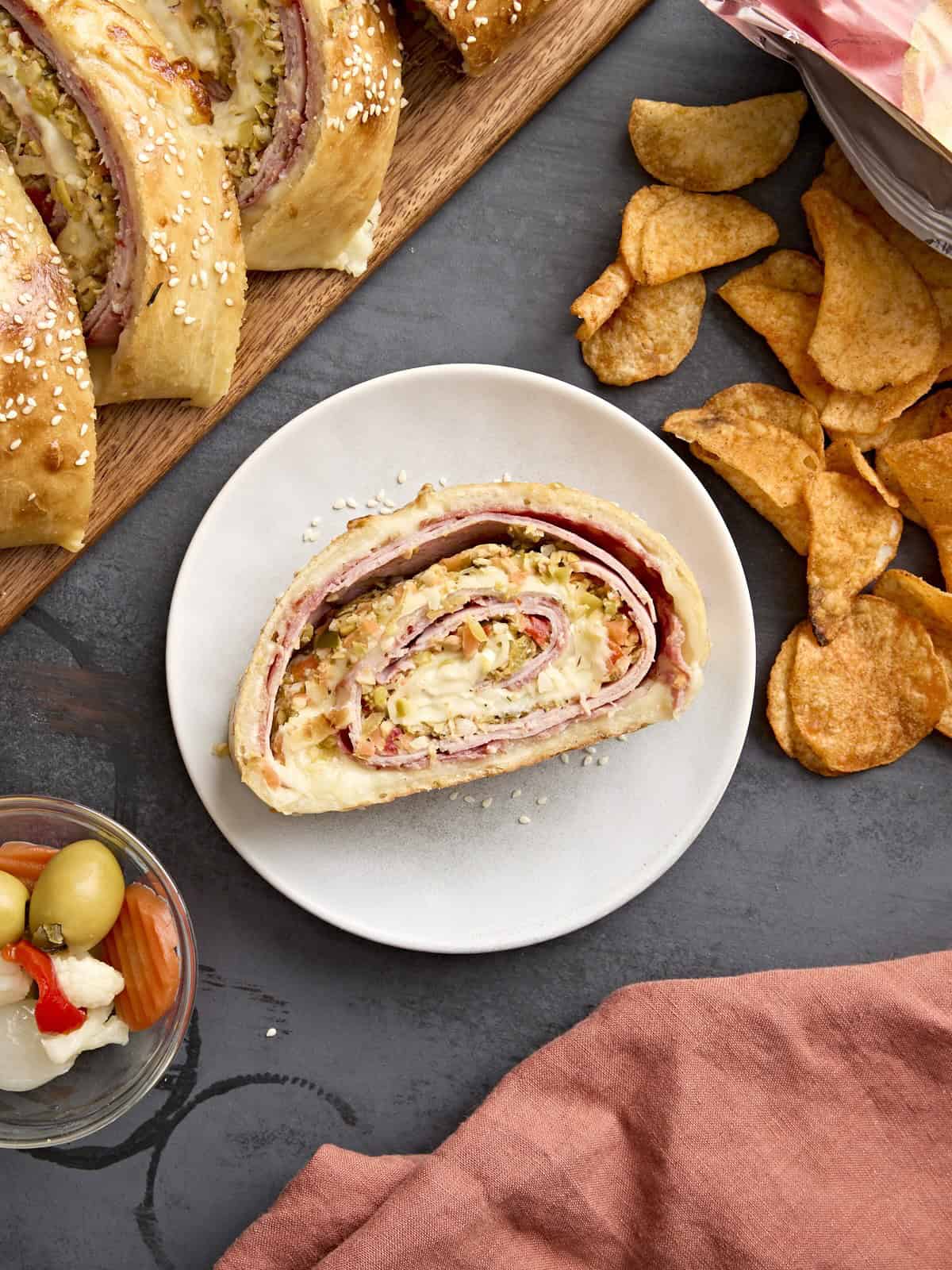 A slice of muffaletta roll up on a plate