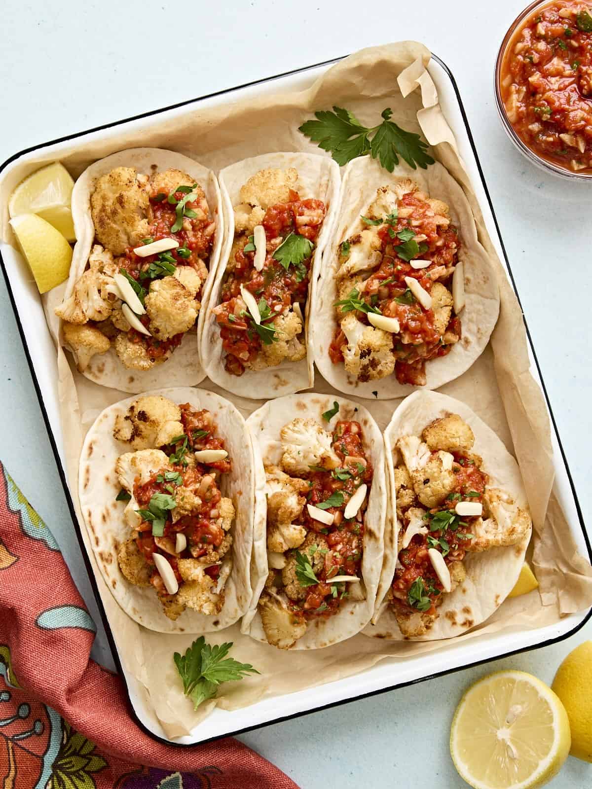 Cauliflower tacos with romesco sauce in a parchment lined baking dish