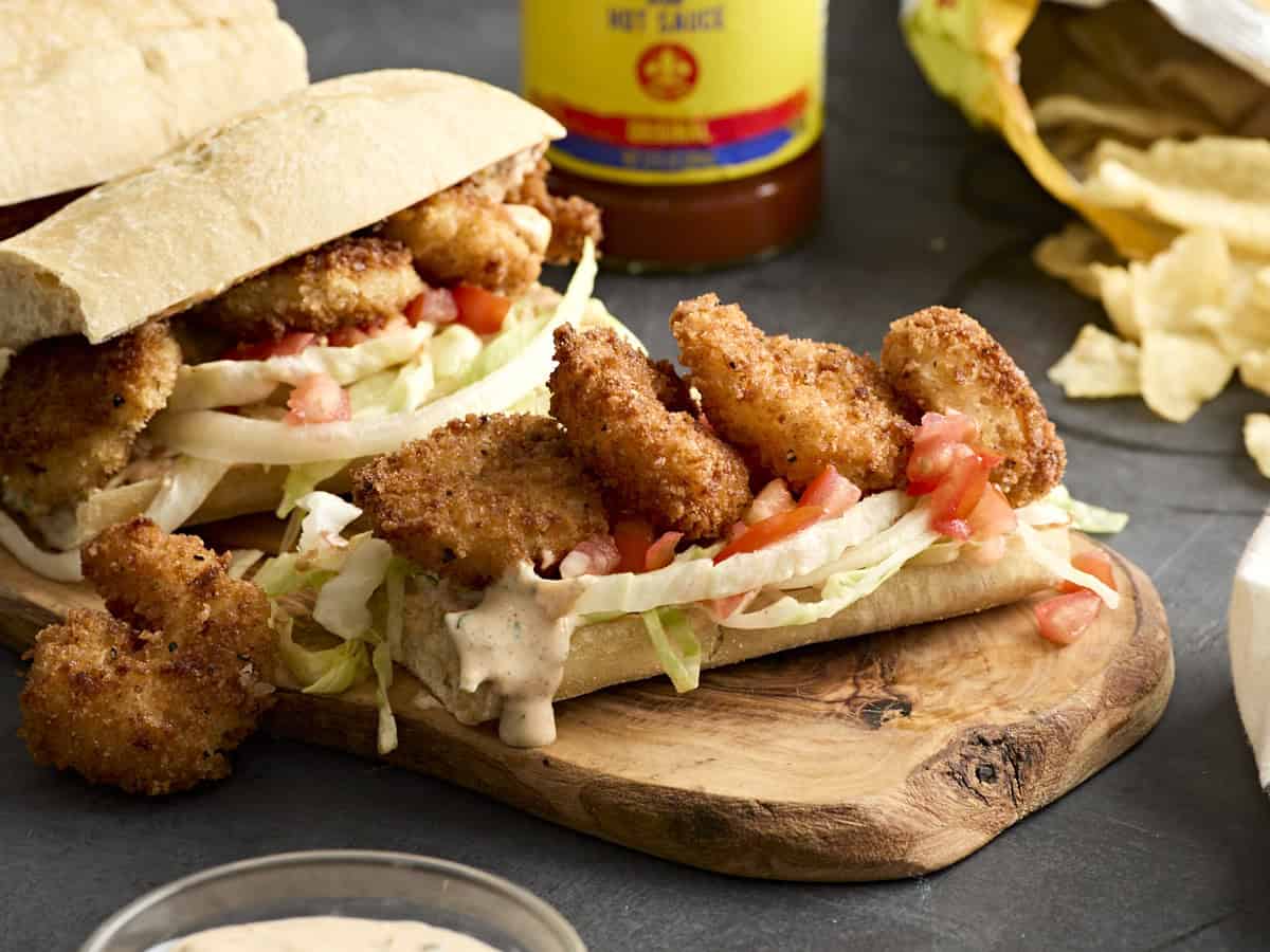 Side view of a shrimp po' boy on a wooden cutting board