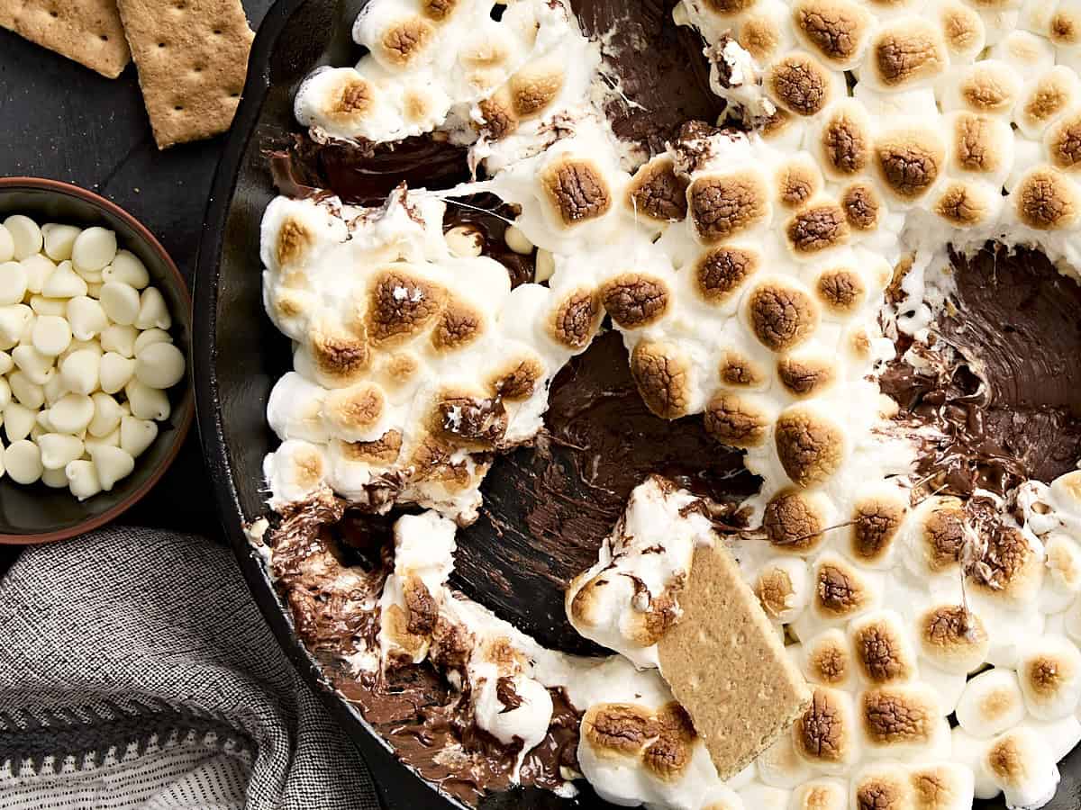 Half eaten s'mores dip with a graham cracker scooping more out