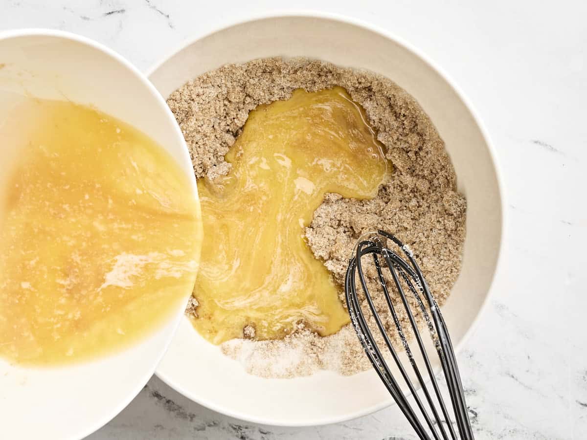 Pouring butter tart wet ingredients into the dry ingredients in a mixing bowl.