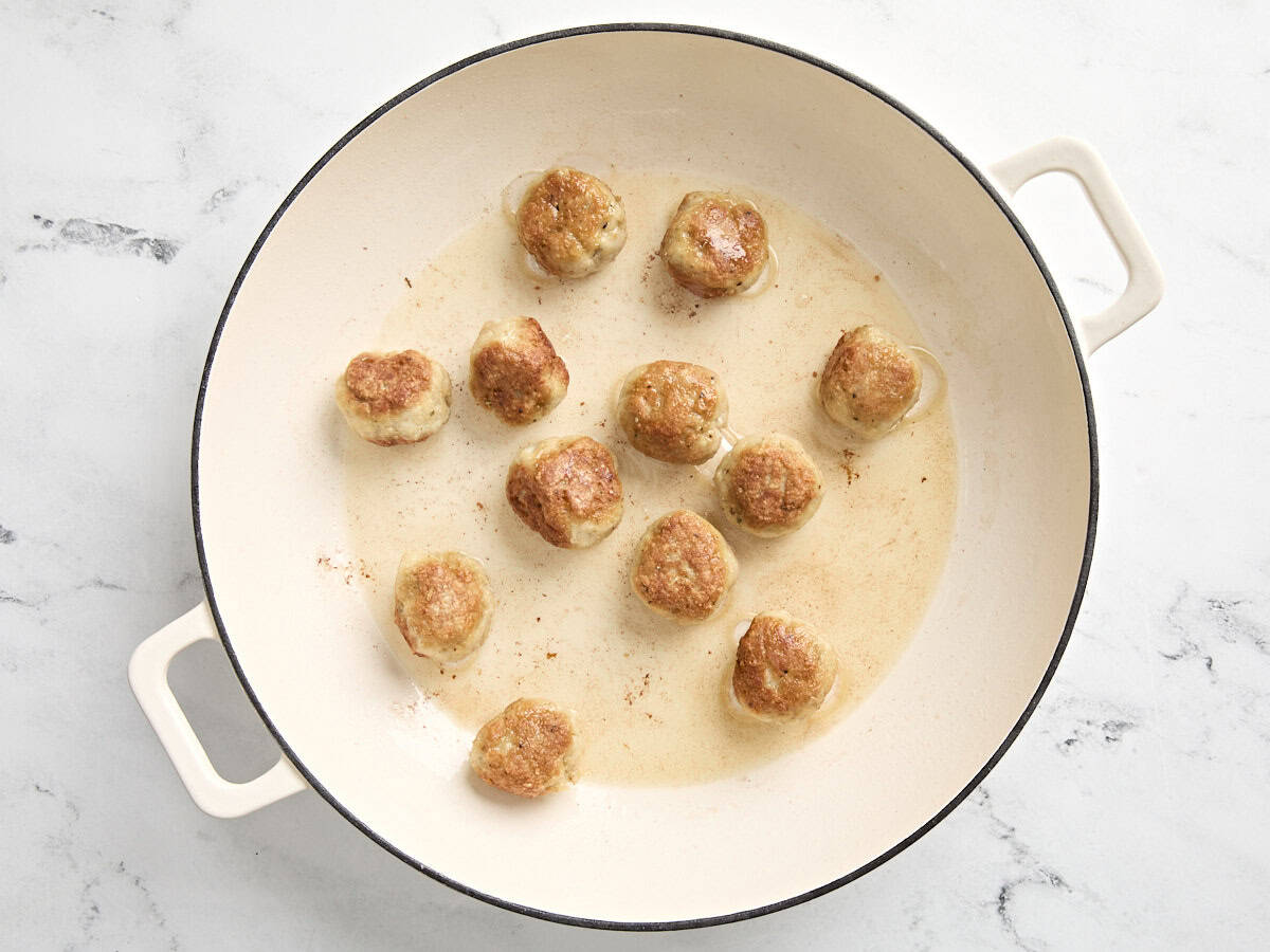 chicken meatballs cooking in a large skillet