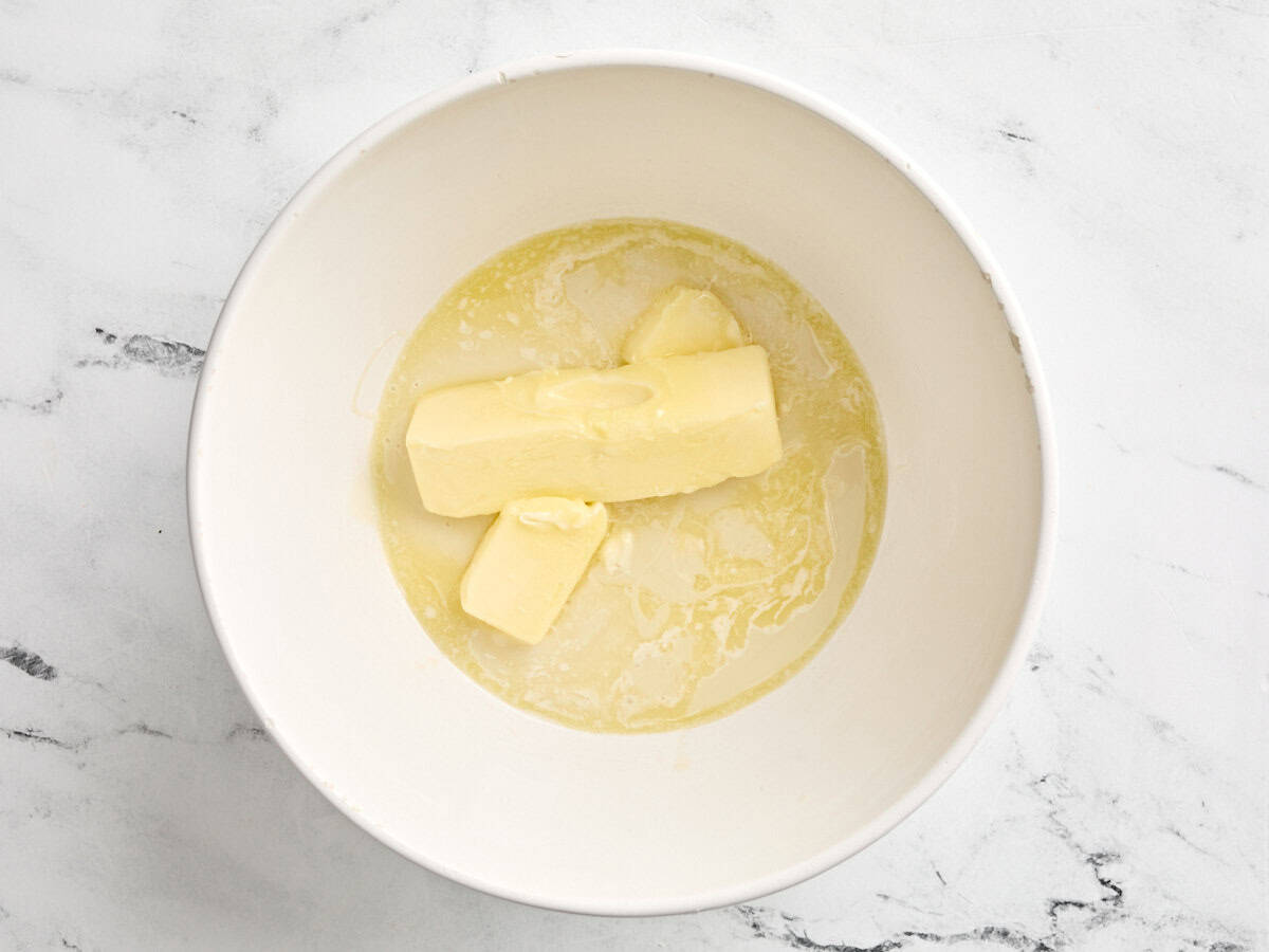 Two sticks of butter and condensed milk in a mixing bowl.