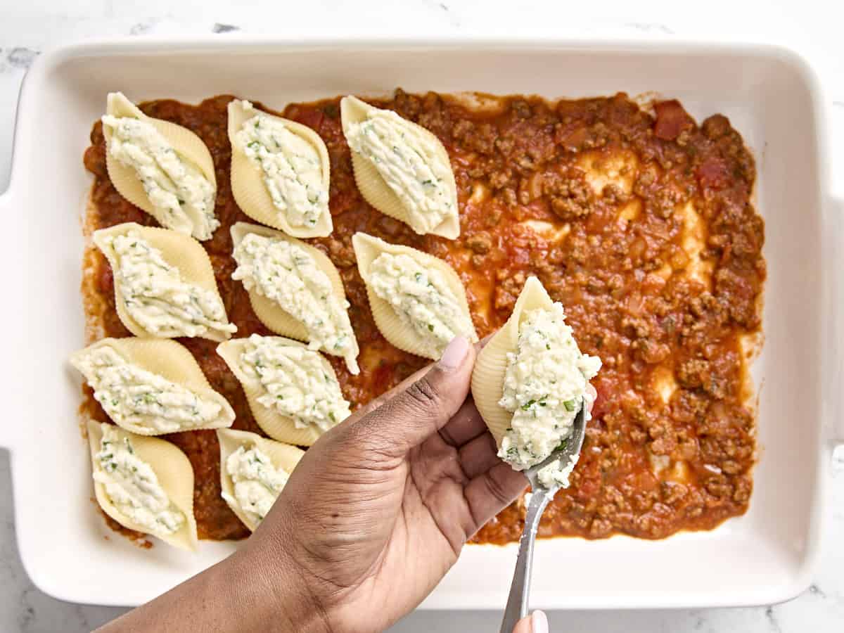 Stuffing jumbo shells with cheese mixture.