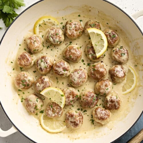 Overhead view of Chicken meatballs in a large skillet with a lemon cream sauce.