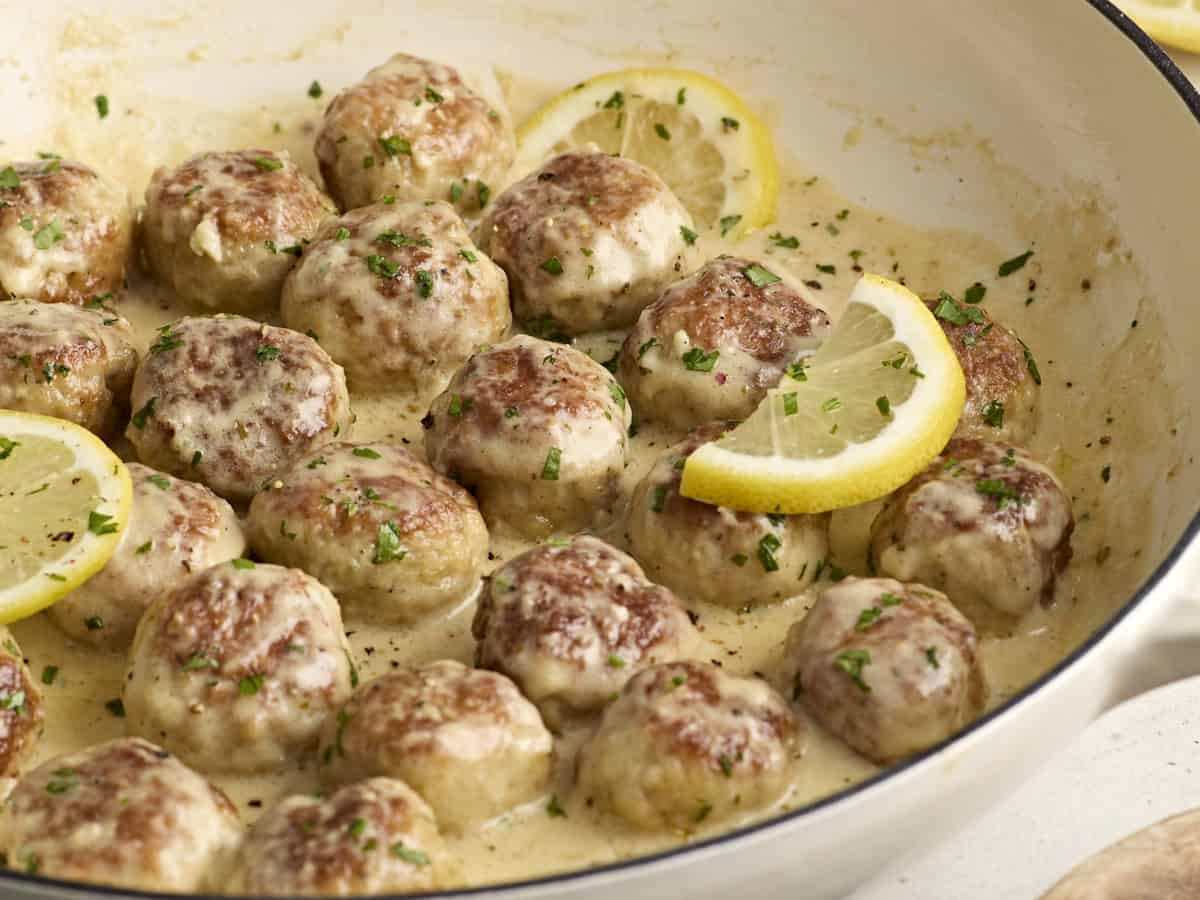 Side view of chicken meatballs in a large skillet with cream sauce.