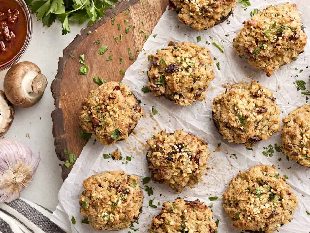 Overhead view of stuffed mushrooms on a wooden chopping board.