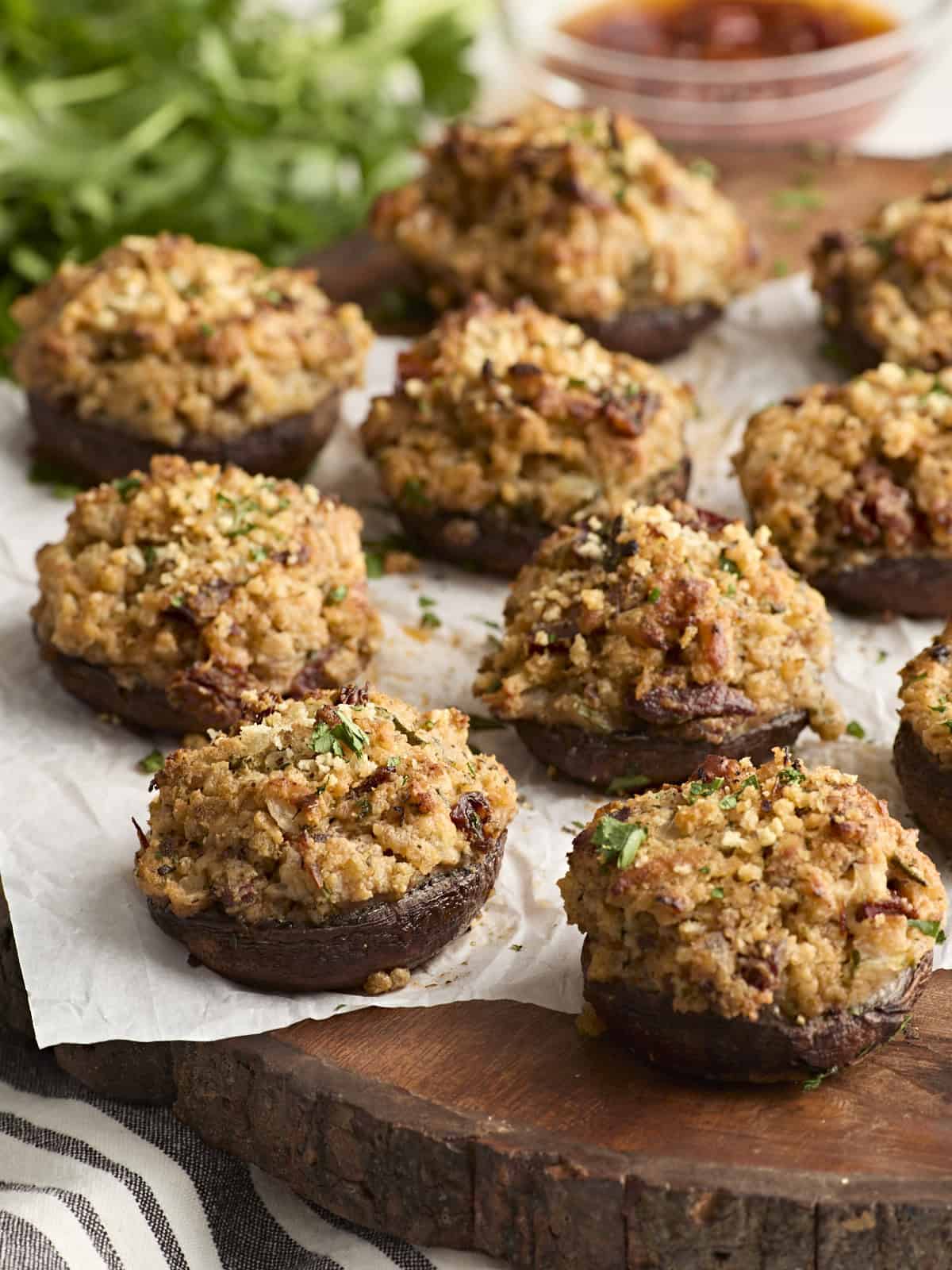 Side view of stuffed mushrooms on a wooden chopping board.