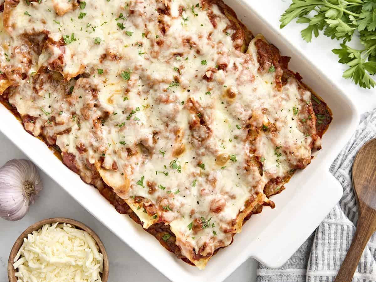 Overhead view of stuffed shells in a casserole dish with a wooden spoon on the side.