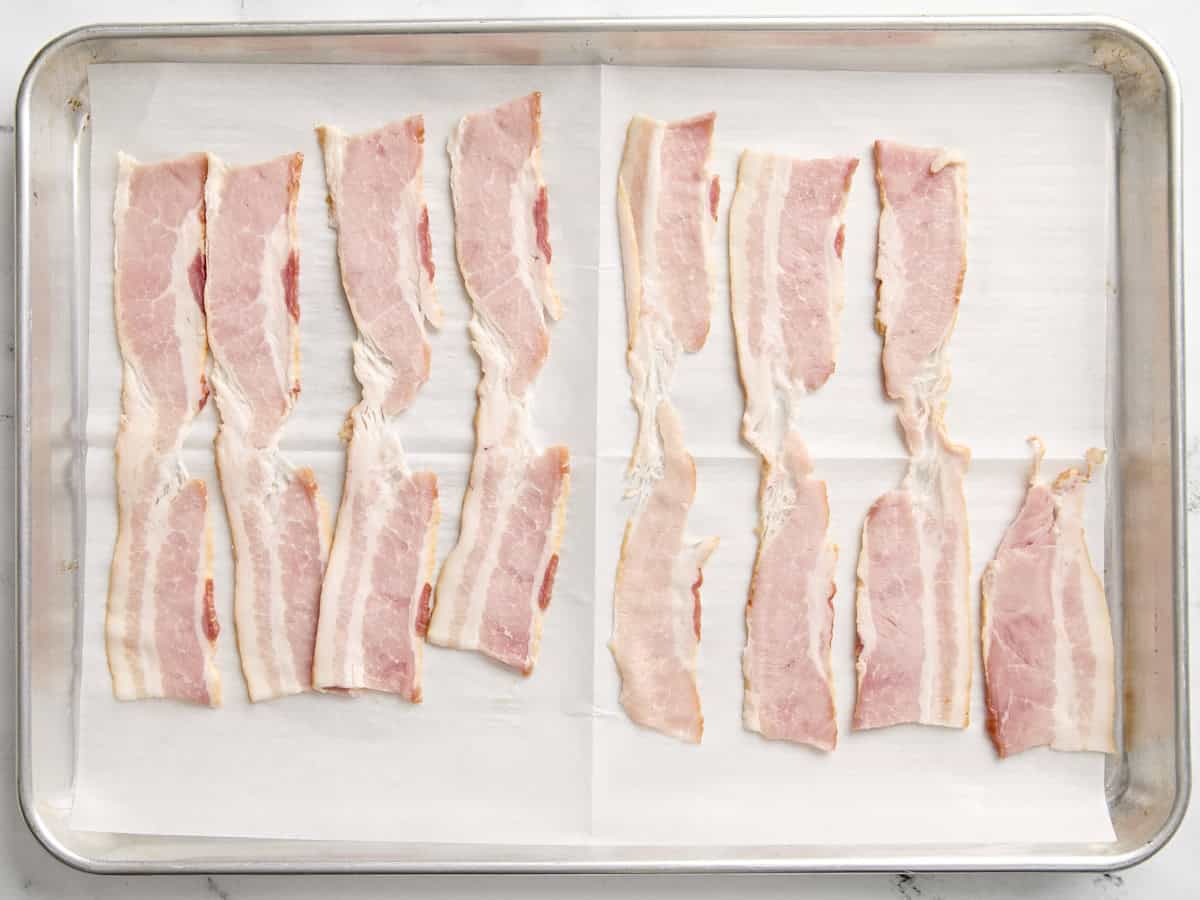 Raw bacon on a baking sheet.