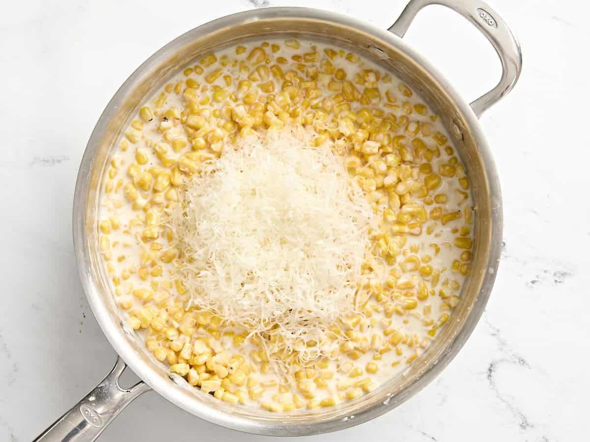 Parmesan added to creamed corn in a saucepan.