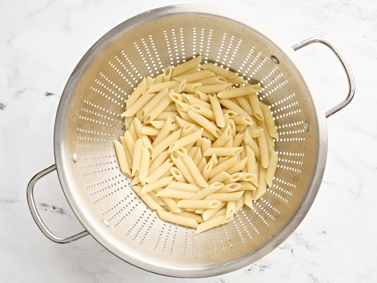 Cooked mostaccioli pasta in a colander.