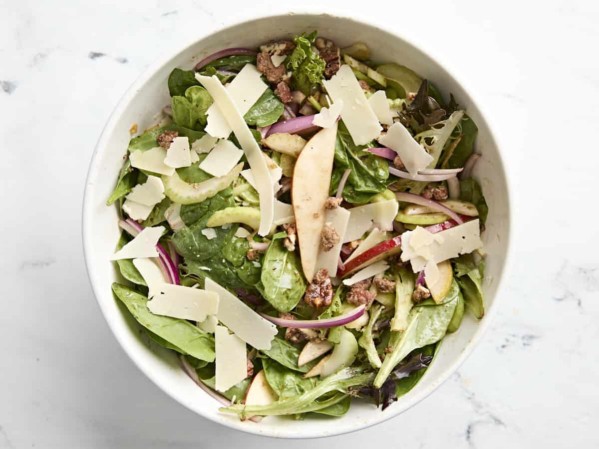 Pear, celery and pecan salad topped with Parmesan in a bowl.