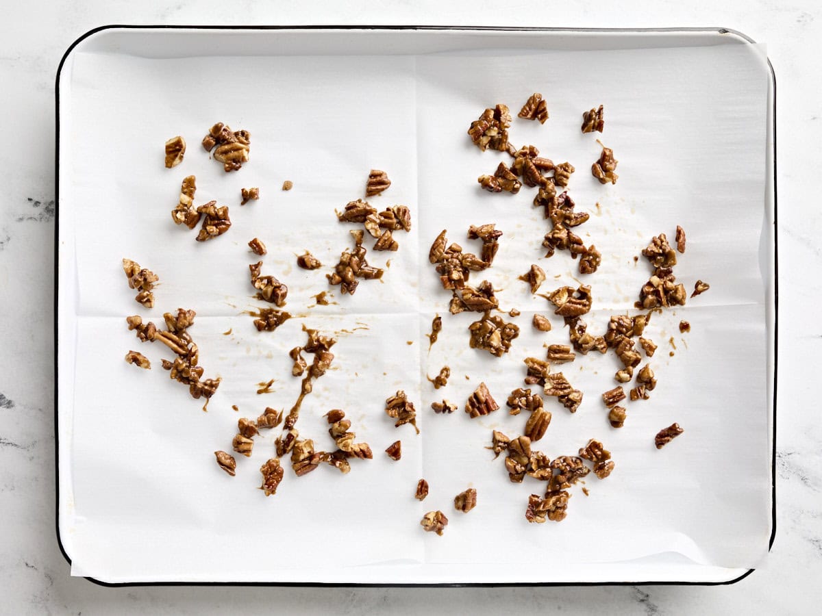 Candied pecans cooling off on a baking sheet.