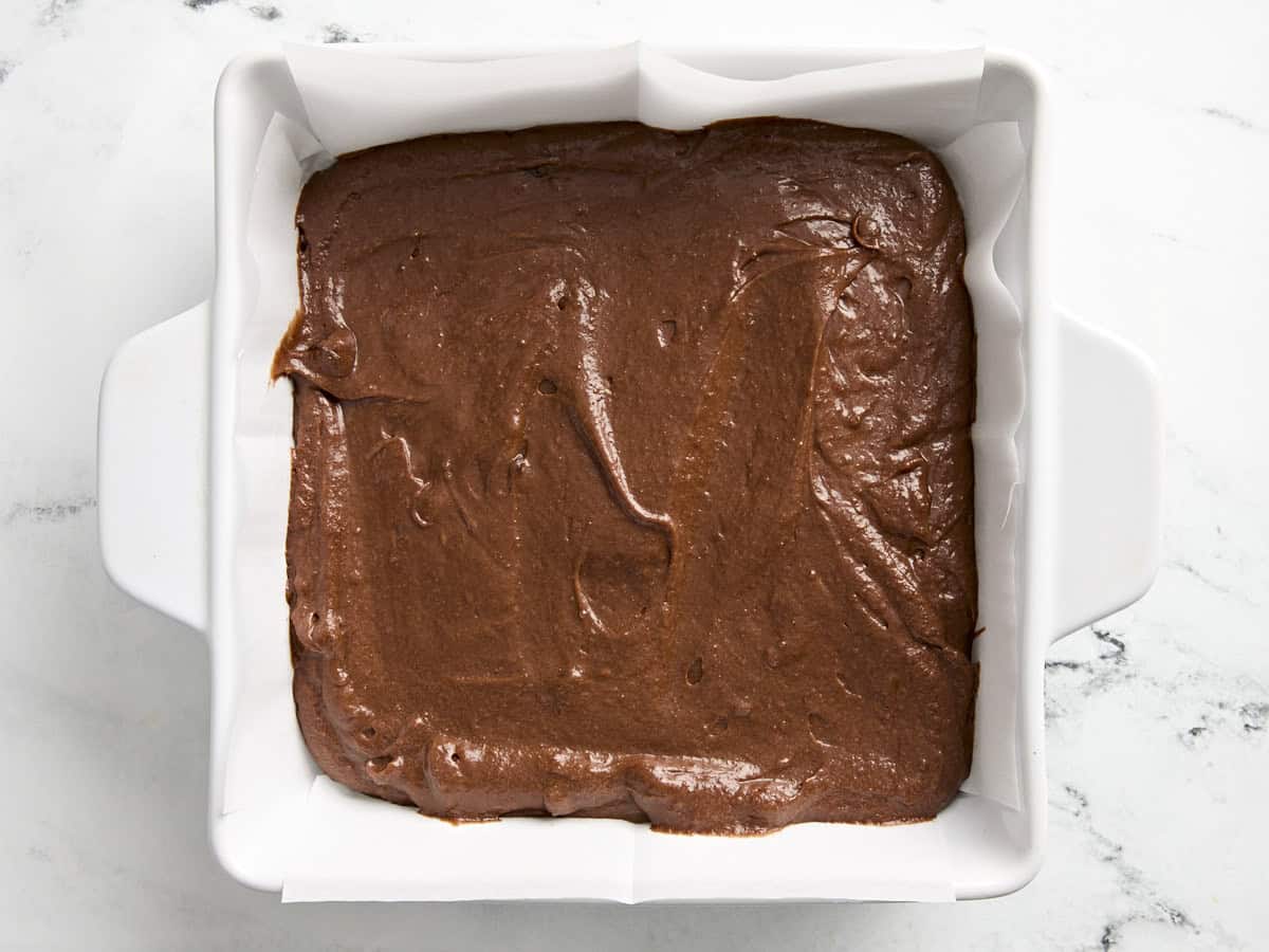 Pumpkin brownie batter in a lined baking dish.