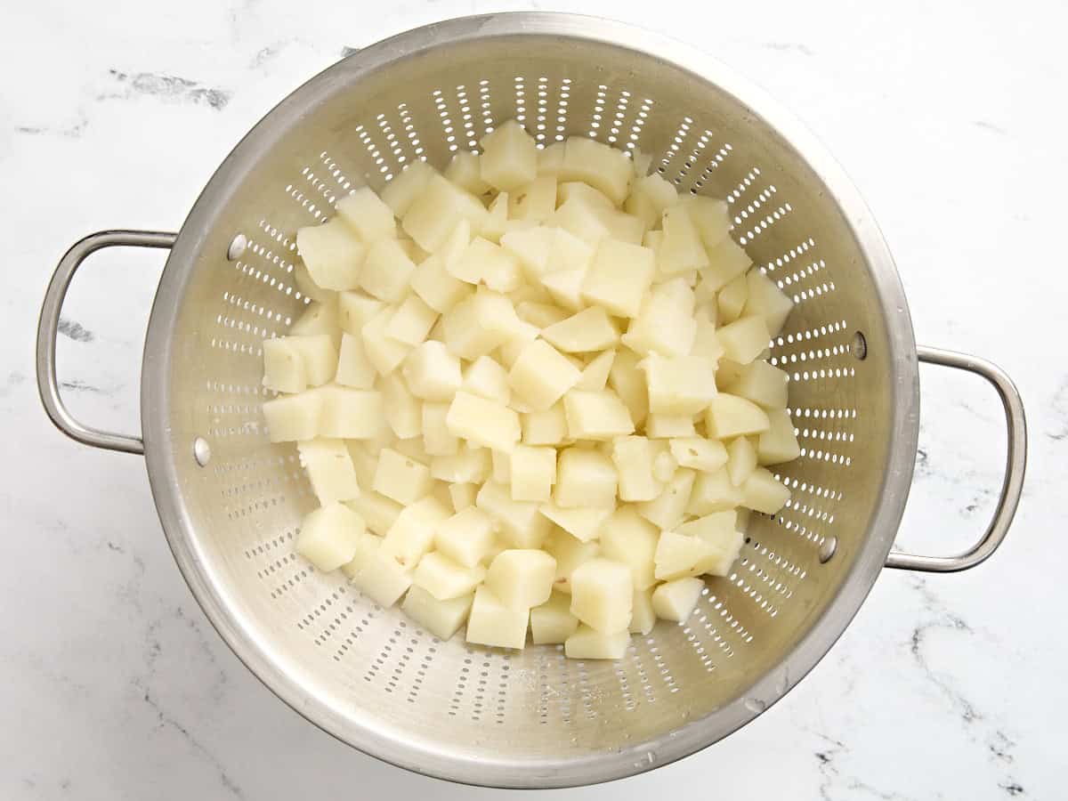 Cooked diced potatoes in a colander.