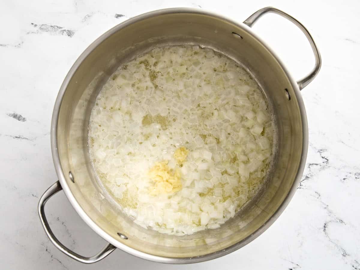 Minced garlic added to a saucepan with diced onions and garlic.