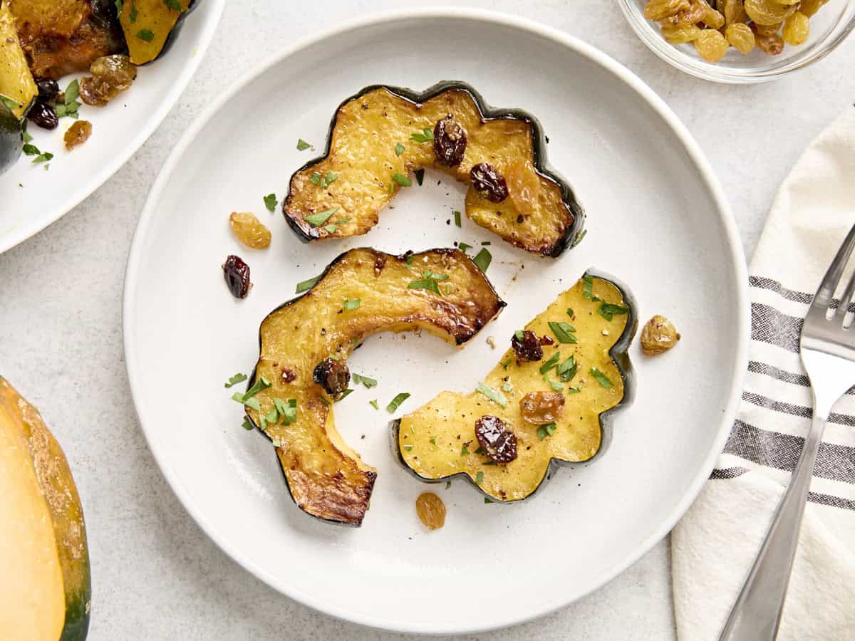 Overhead view of roasted acorn squash slices on a white plate.