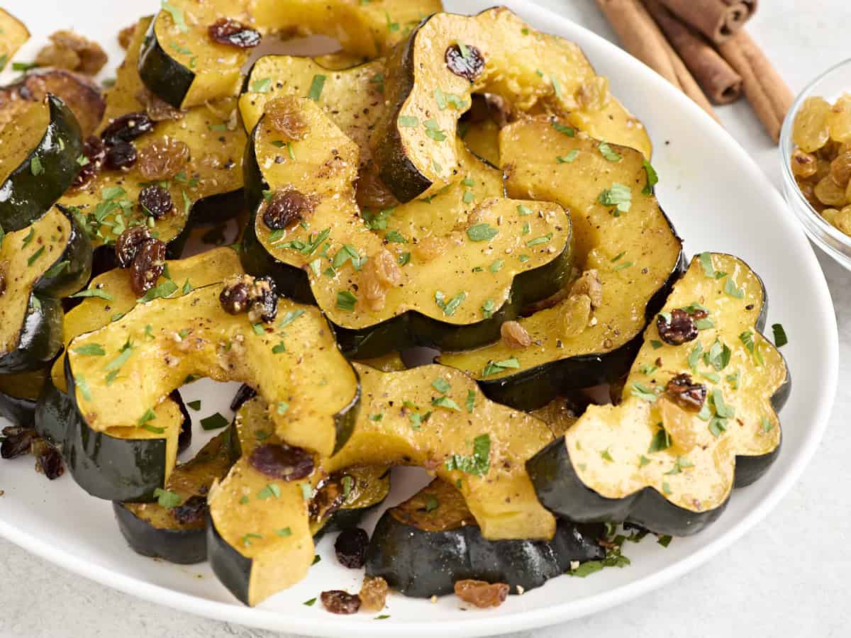 Side view close up of roasted acorn squash slices on a white serving platter.