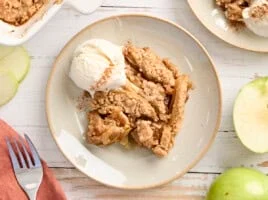 Overhead view of apple crumble on a plate with a scoop of vanilla ice cream.