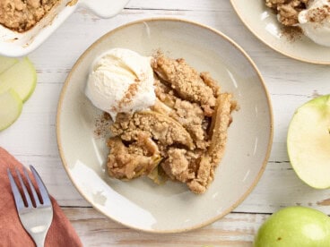 Overhead view of apple crumble on a plate with a scoop of vanilla ice cream.