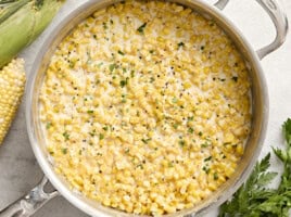 Overhead view of creamed corn in a sauce pan garnished with fresh parsley.