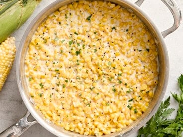 Overhead view of creamed corn in a sauce pan garnished with fresh parsley.