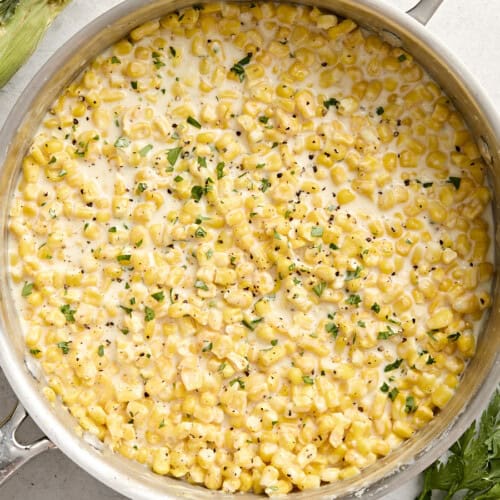 Overhead view of creamed corn in a sauce pan garnished with fresh parsley.