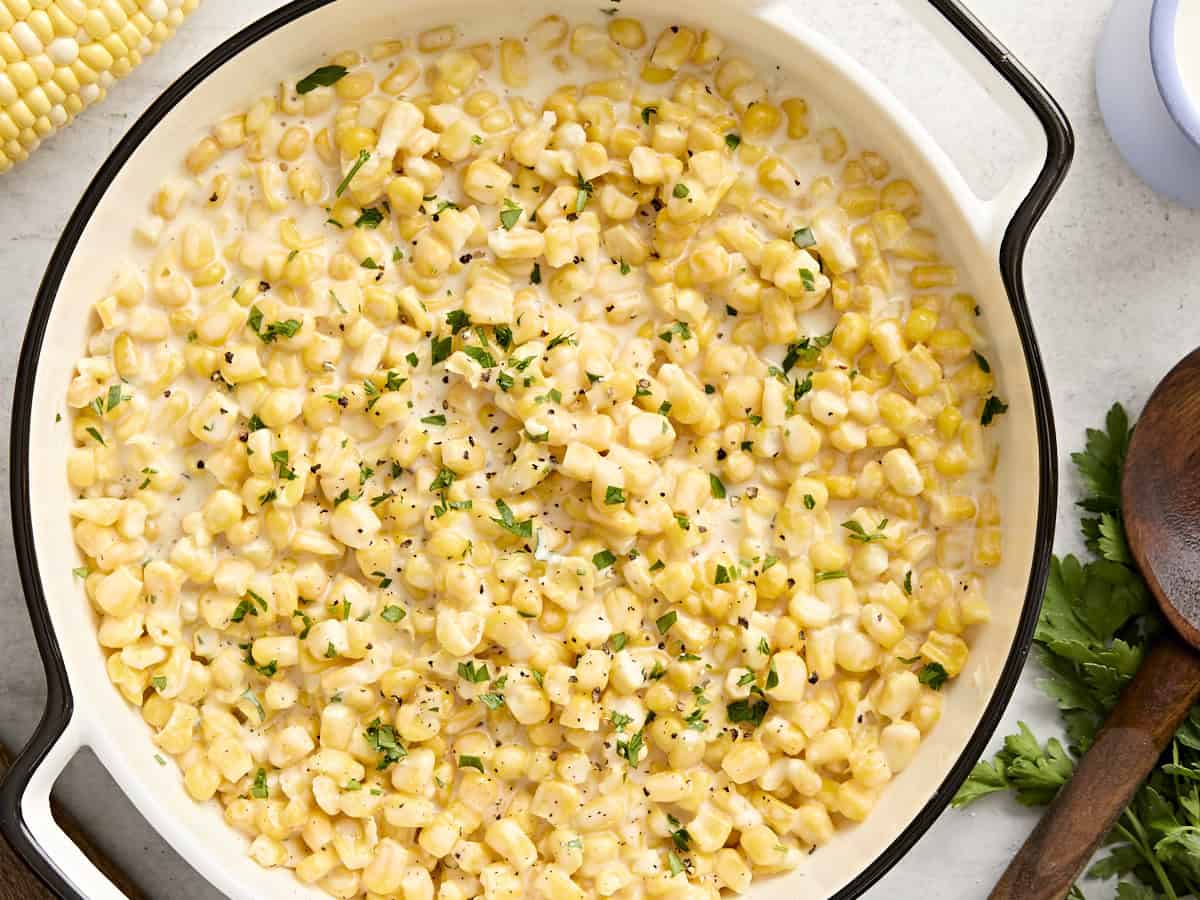 Overhead view of creamed corn in a serving dish garnished with fresh parsley.