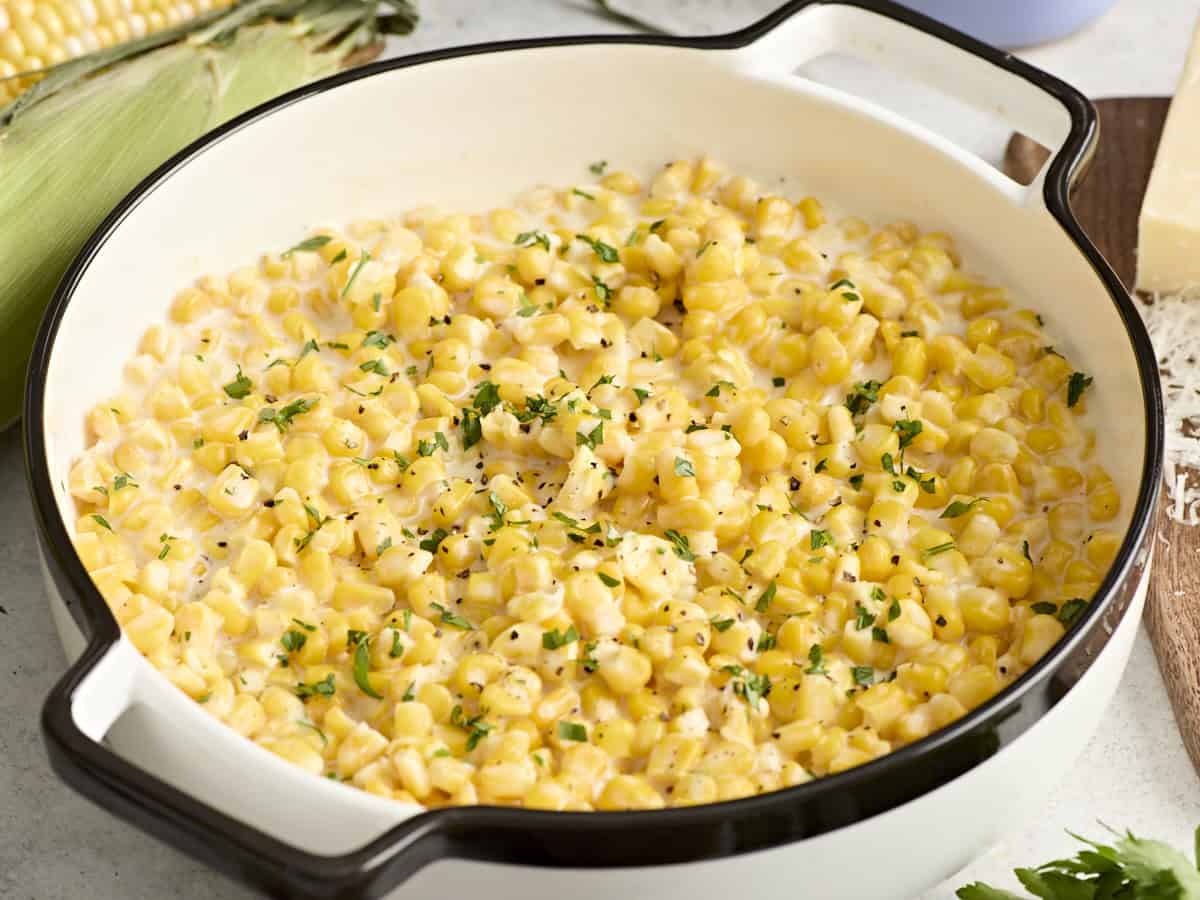 Side view of creamed corn in a serving dish garnished with fresh parsley.