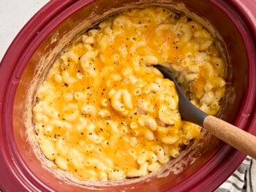 Overhead view of crock pot mac and cheese with a large spoon lifting some out.