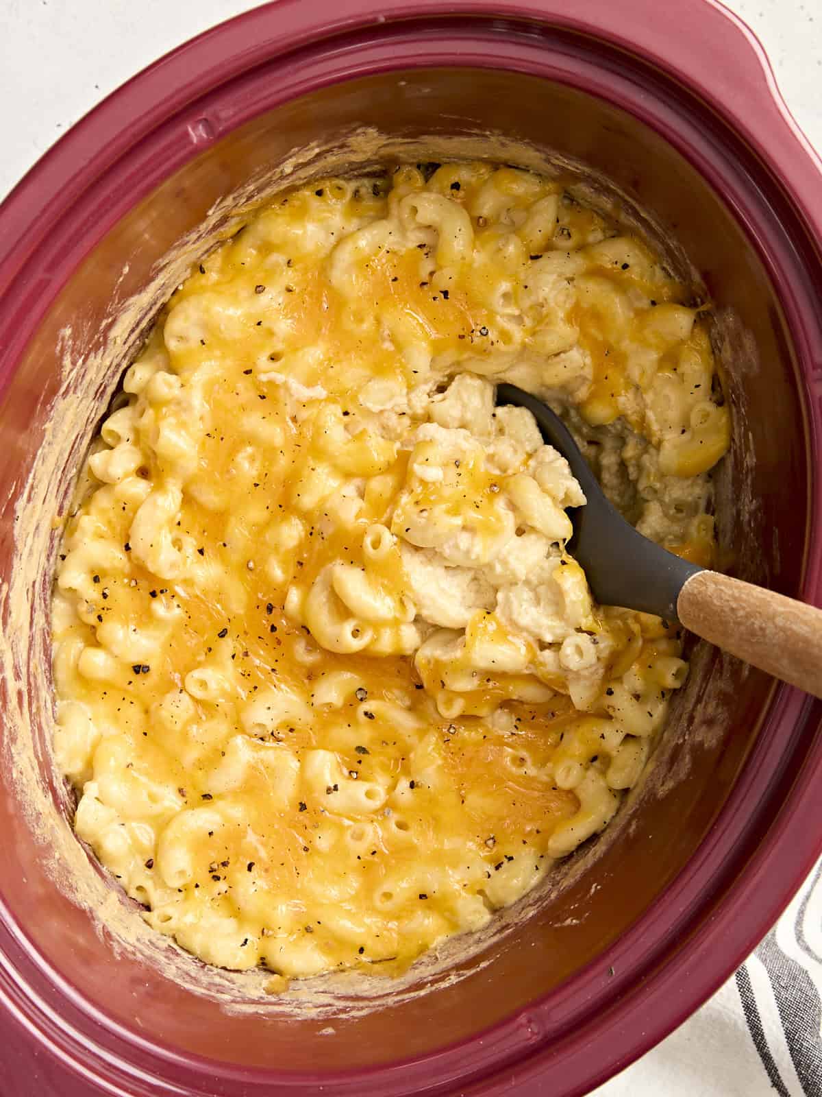 Overhead view of crock pot mac and cheese with a large spoon lifting some out.