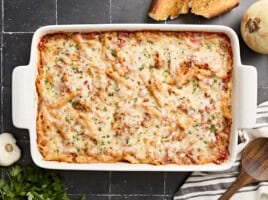 Overhead view of baked mostaccioli with a wooden serving spoon on the side.