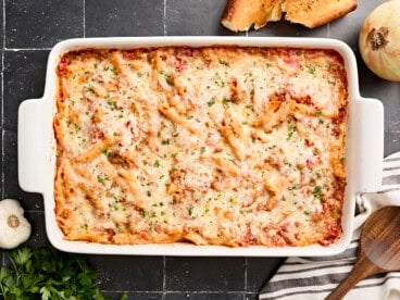 Overhead view of baked mostaccioli with a wooden serving spoon on the side.