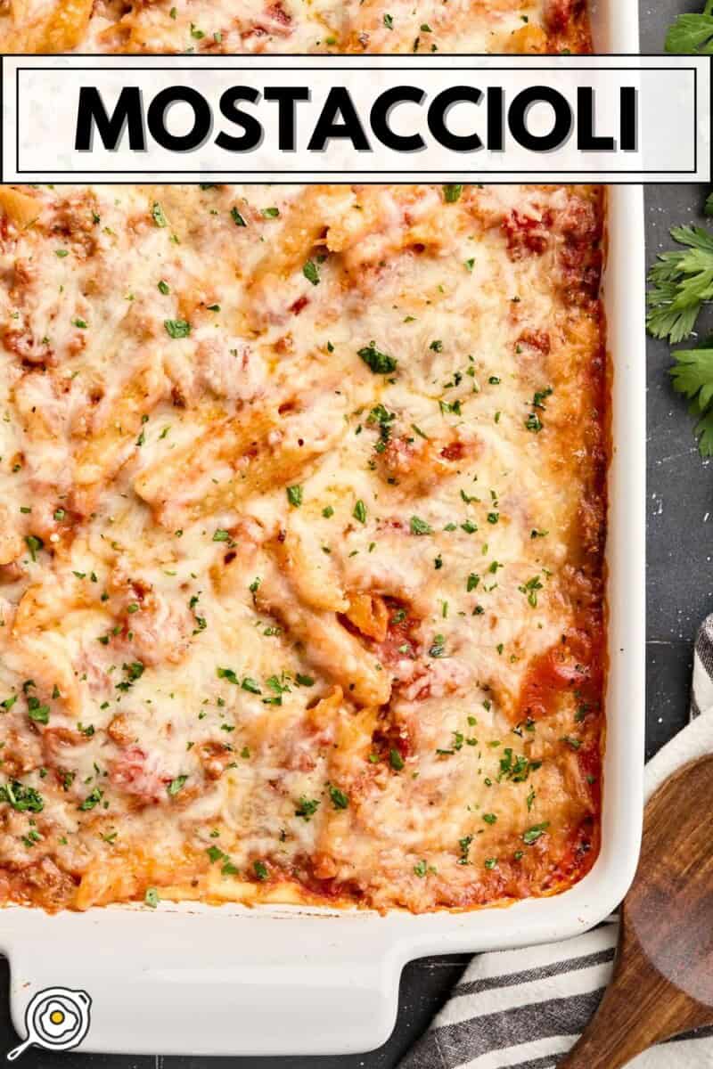 Overhead view of baked mostaccioli in a white baking dish with title text at the top.