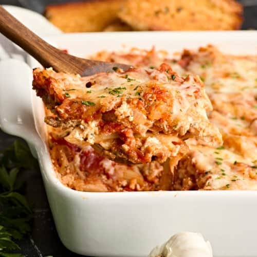 Side view of baked mostaccioli with a serving being lifted out of the pan.