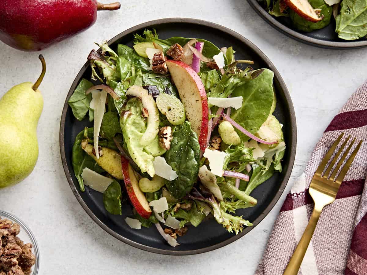 Overhead view of pear celery pecan salad on a black plate.