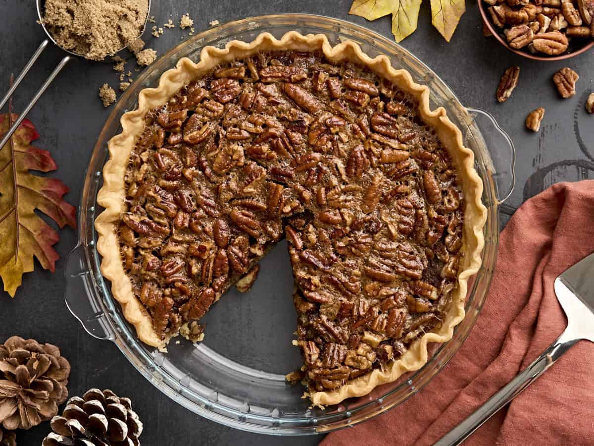 Pecan pie in a glass pie dish with a slice missing.