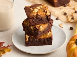 A stack of pumpkin brownies on a plate.